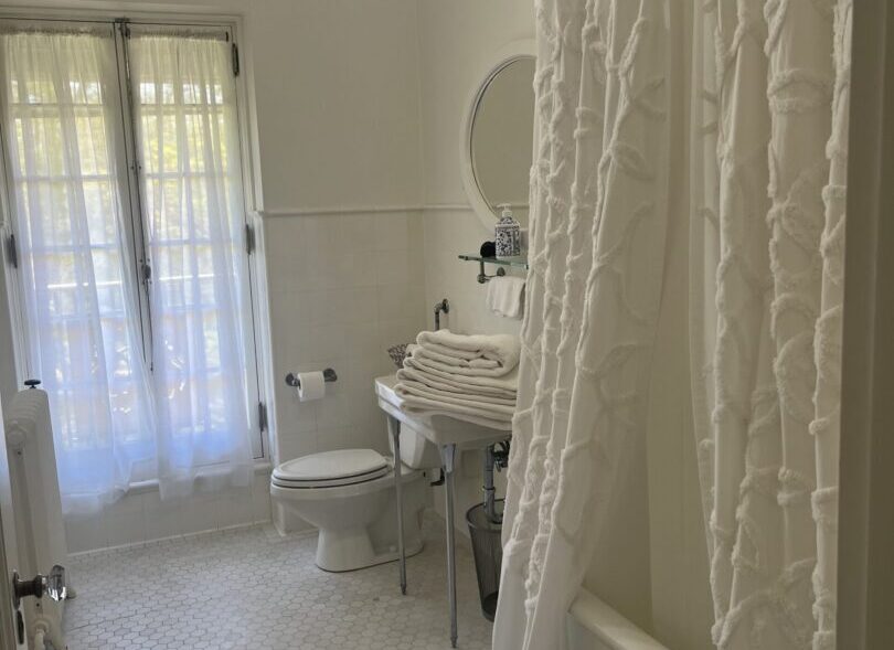 A bright bathroom with white decor and a shower curtain.